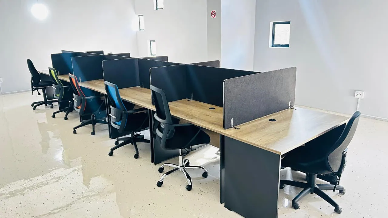 Rows of co-working desks with privacy dividers and coloured task chairs inside the ANBI centre