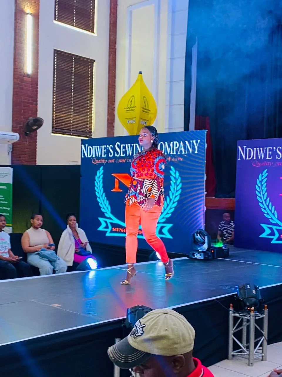 A model in a bold orange outfit on the Ndiwe's Sewing Company runway