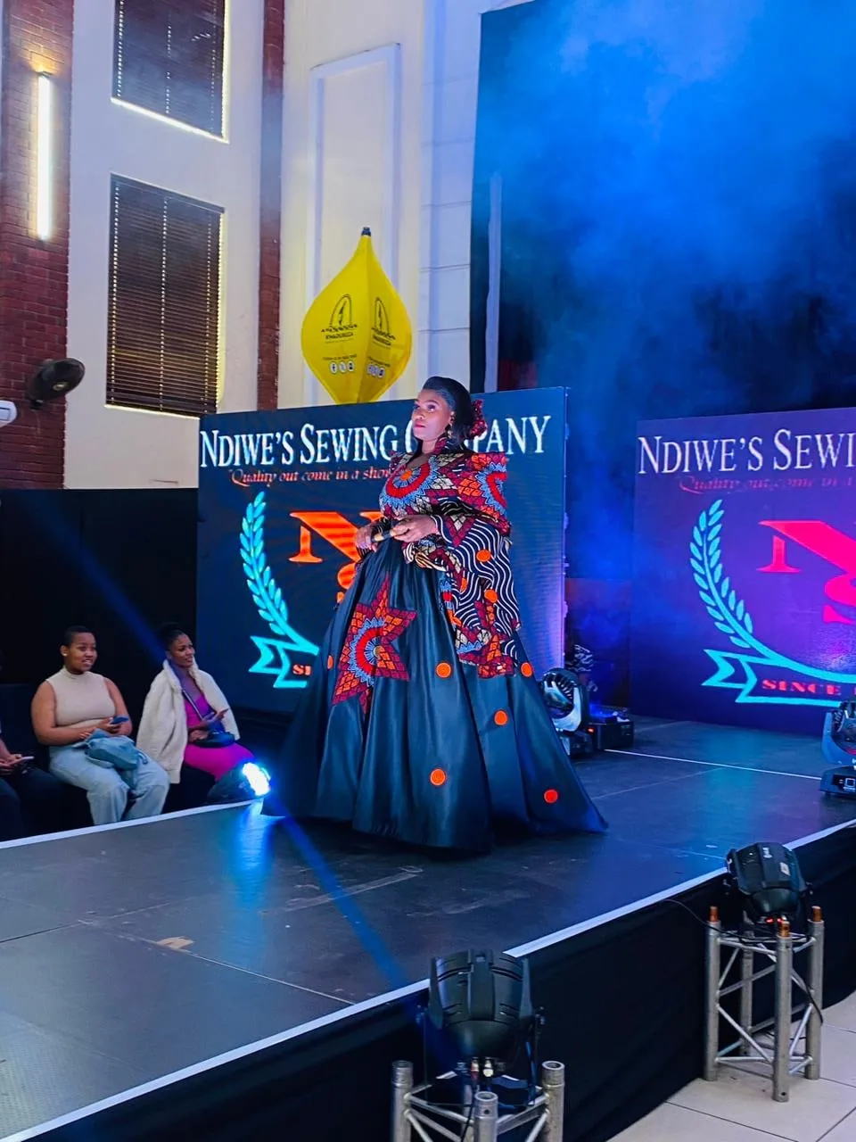 A model in an elaborate red and black gown on the Ndiwe's Sewing Company runway