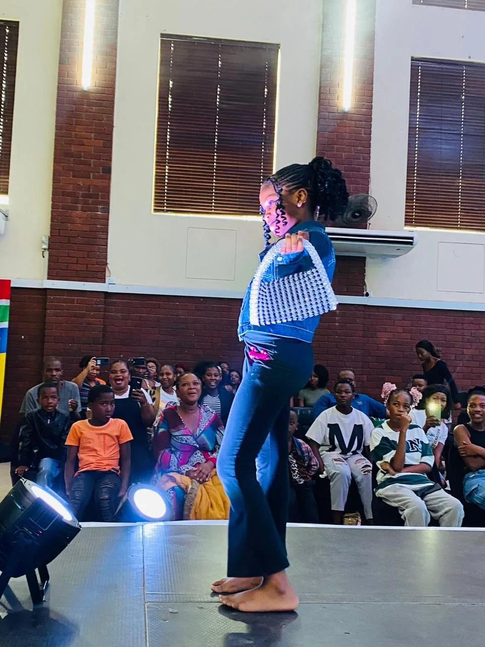 A model pausing to pose in a blue top and jeans as the audience watches