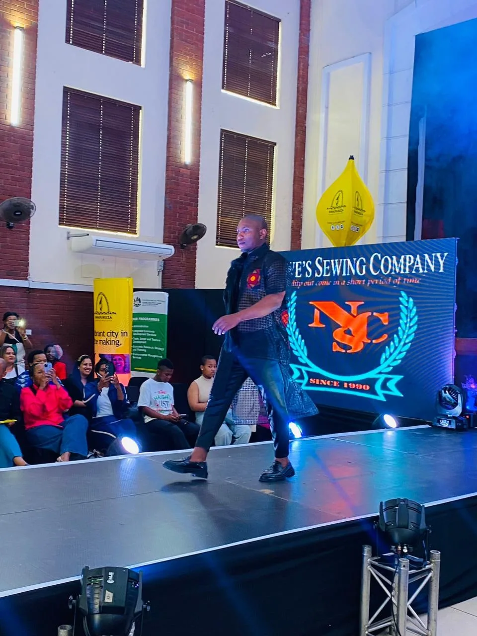 A designer on stage in a branded shirt during the showcase