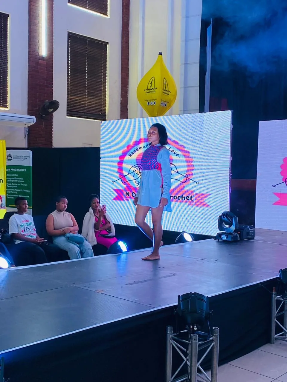 A model on the runway in front of the event backdrop