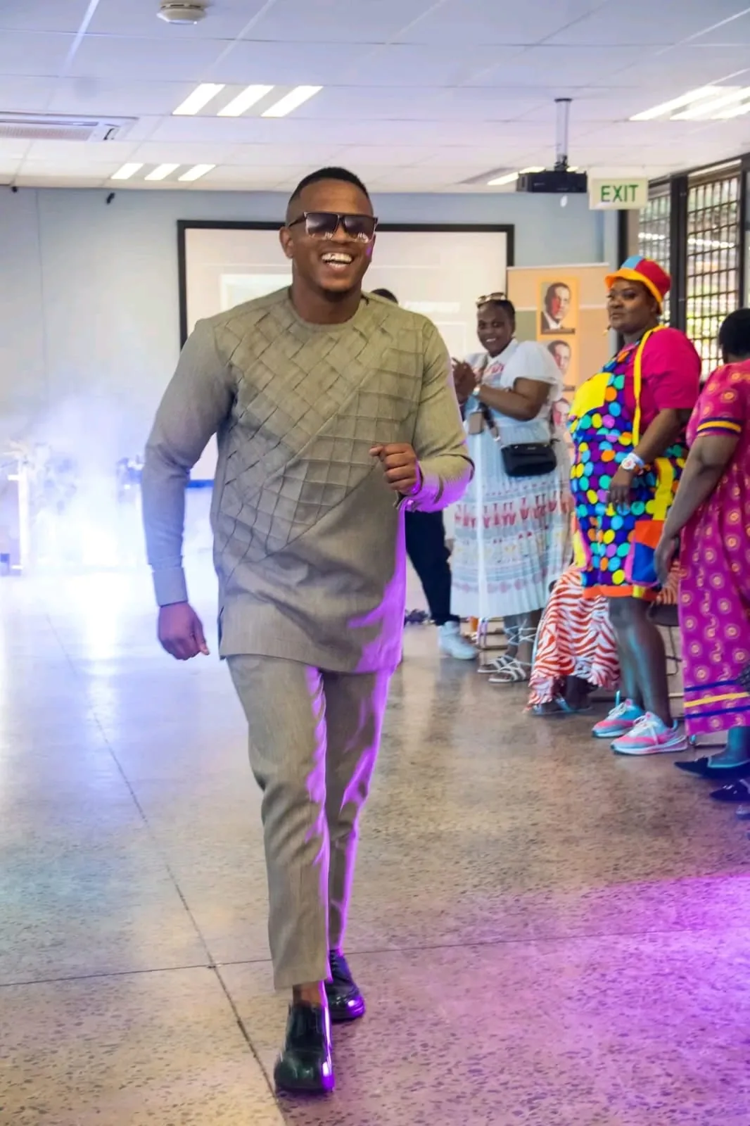 A male model in a grey traditional outfit walking the runway