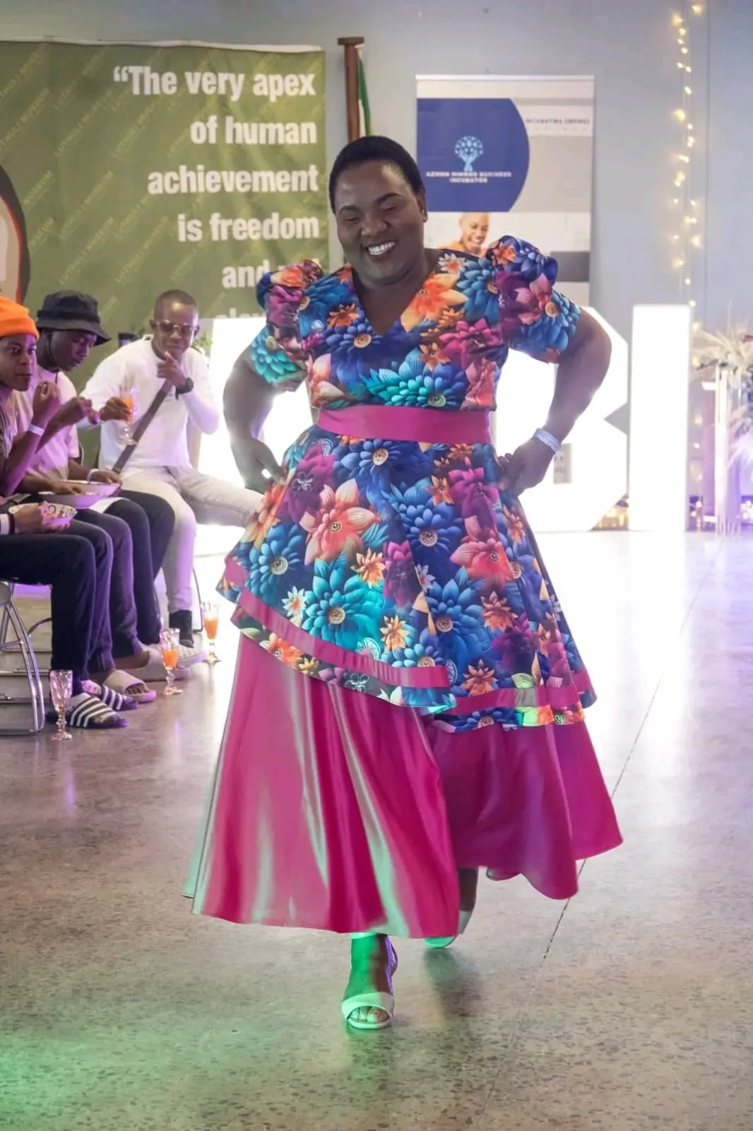 A model in a pink and red print outfit posing on the runway