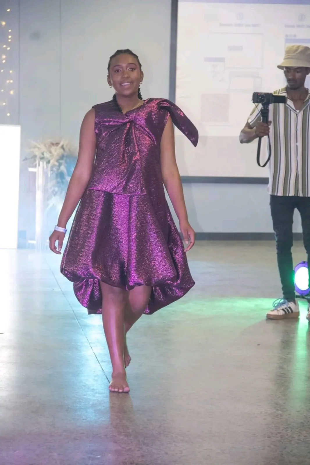 A model in a shimmering purple dress walking the runway