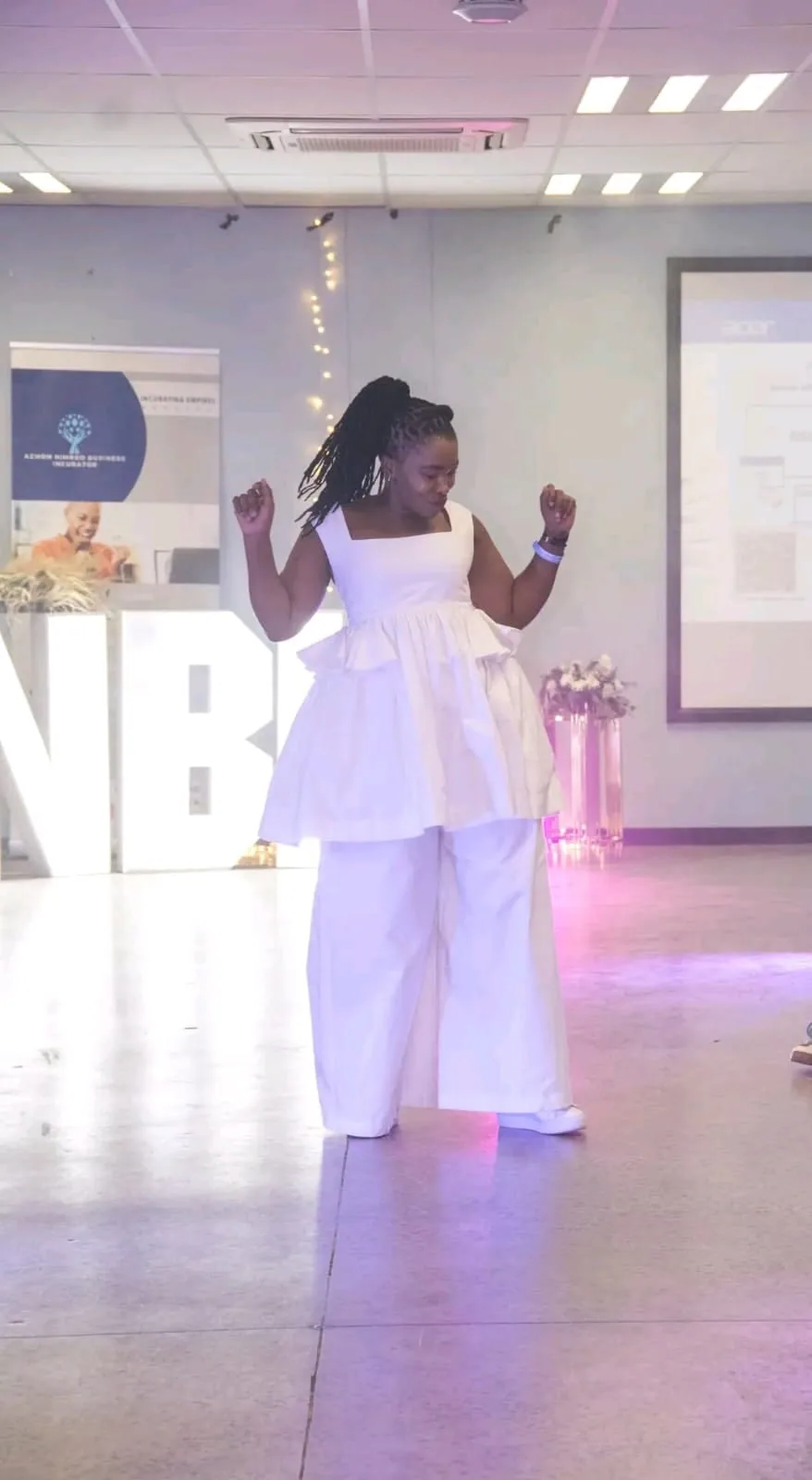 A child dancing in a white outfit in front of the ANBI backdrop