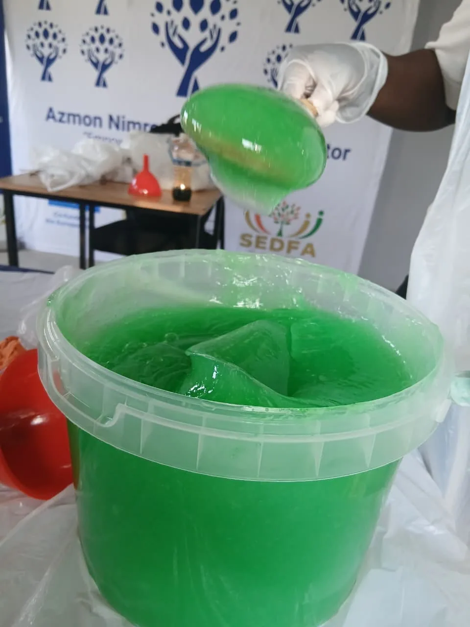 A trainee decanting freshly made green detergent gel during ANBI production training
